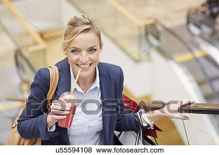 Businesswoman on escalator with shopping and fruit drink View Large Photo Image Stock Photo - Businesswoman on escalator with shopping and fruit drink. Fotosearch