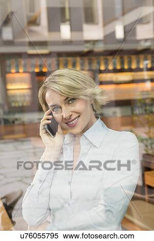Stock Photography - Businesswoman on telephone call, view through window. Fotosearch