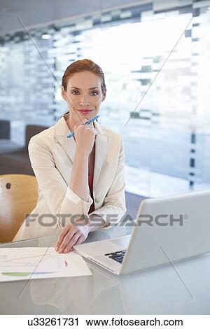 Stock Image - Businesswoman sitting at desk, writing activity. Fotosearch