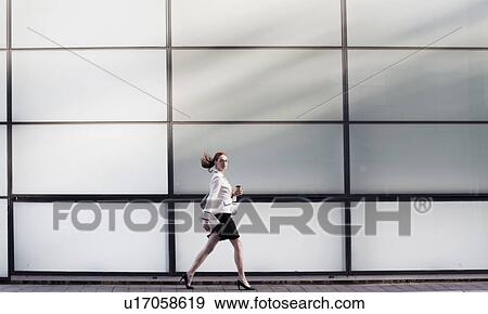 Businesswoman walking holding hot drink View Large Photo Image Stock Photo - Businesswoman walking holding hot drink. Fotosearch