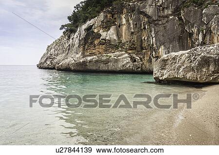Stock Photo - Cliffs and beach, Cala Goloritze, Sardinia, Italy. Fotosearch
