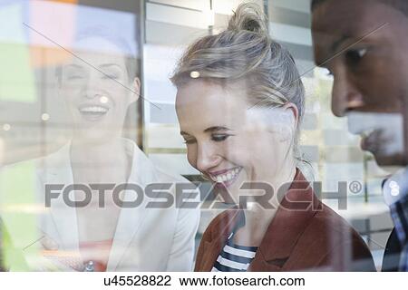 Stock Image - Colleagues laughing, view through window. Fotosearch