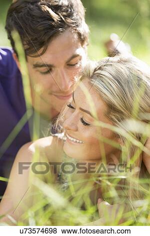 Stock Photo - Couple lying on grass, close up. Fotosearch