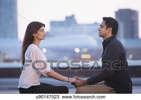 Stock Image - Couple meditating on rooftop. Fotosearch