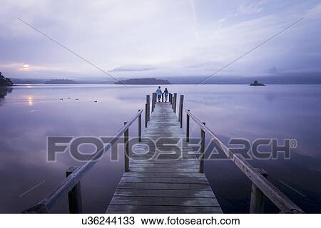 Couple on pier by tranquil lake, Cumbria, England, UK View Large Photo Image Stock Image - Couple on pier by tranquil lake, Cumbria, England, UK. Fotosearch