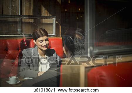 Stock Image - Couple sitting in restaurant booth. Fotosearch