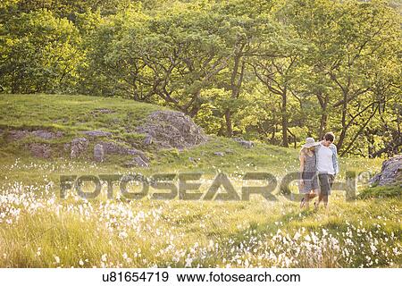 Stock Photo - Couple walking in field, Cumbria, England, UK. Fotosearch