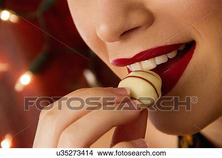 Cropped close up of young woman eating chocolate View Large Photo Image Picture - Cropped close up of young woman eating chocolate. Fotosearch