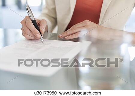 Stock Image - Cropped image of businesswoman signing paperwork. Fotosearch