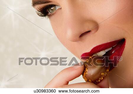 Cropped image of young woman eating chocolate View Large Photo Image Stock Image - Cropped image of young woman eating chocolate. Fotosearch
