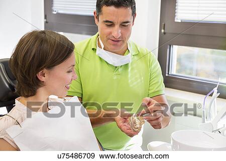 Stock Photo - Dentist showing woman dentures. Fotosearch