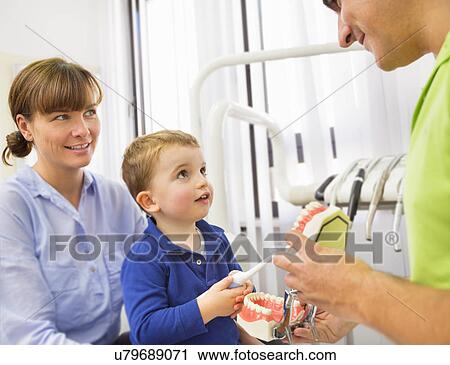 Dentist teaching boy on mothers lap how to brush teeth View Large Photo Image Stock Image - Dentist teaching boy on mothers lap how to brush teeth. Fotosearch
