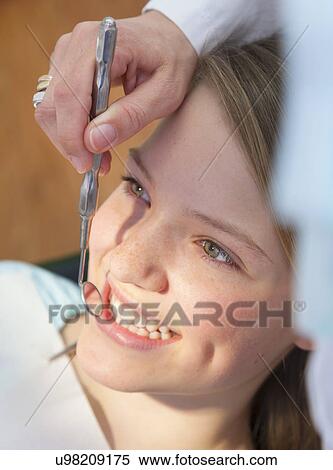 Dentist using dental mirror on teenage girl View Large Photo Image Stock Photography - Dentist using dental mirror on teenage girl. Fotosearch