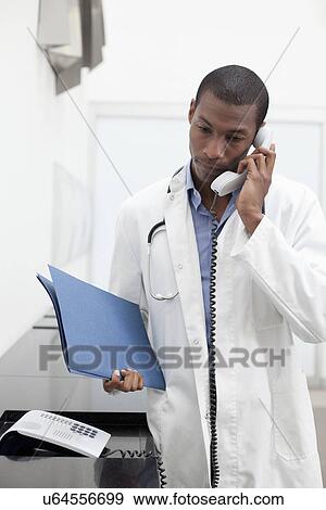 Doctor on telephone call, holding paperwork View Large Photo Image Stock Photo - Doctor on telephone call, holding paperwork. Fotosearch
