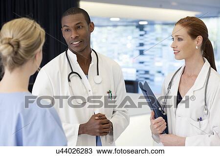 Stock Image - Doctors and nurse having conversation. Fotosearch