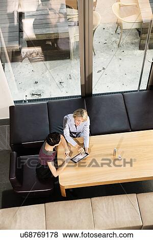 Elevated view of businesswomen using digital tablet View Large Photo Image Stock Photo - Elevated view of businesswomen using digital tablet. Fotosearch