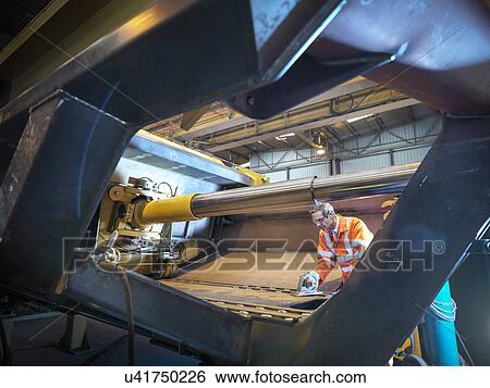 Stock Photograph - Engineer inspecting steel components in factory. Fotosearch