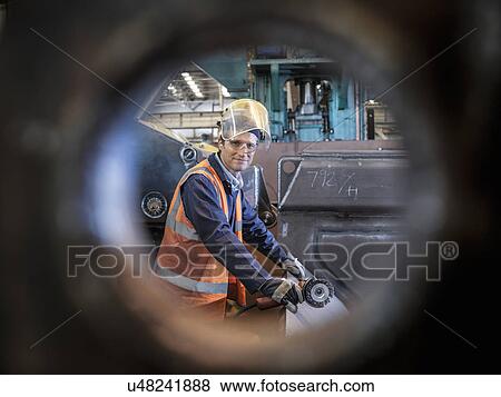 Stock Photo - Engineer portrait in factory viewed through hole in steel. Fotosearch