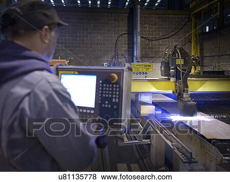 Stock Photo - Engineer using plasma cutter in factory. Fotosearch