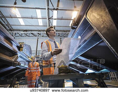Engineer with engineering drawings in factory View Large Photo Image Stock Photo - Engineer with engineering drawings in factory. Fotosearch