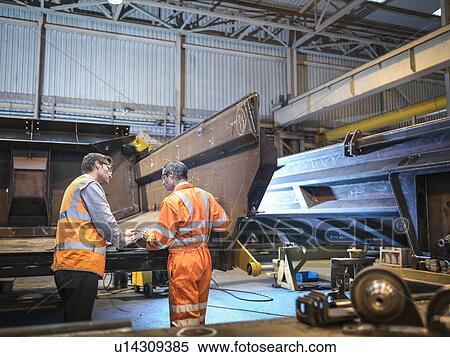 Stock Photography - Engineers discussing engineering drawings in factory. Fotosearch