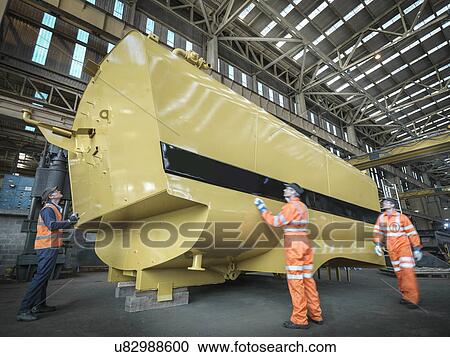 Engineers inspecting large tank in factory View Large Photo Image Stock Image - Engineers inspecting large tank in factory. Fotosearch