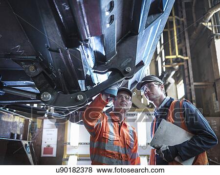Stock Photo - Engineers inspecting work in factory. Fotosearch