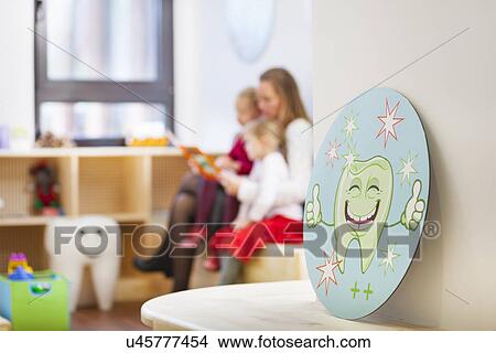 Family in dentists waiting room, picture of tooth in foreground View Large Photo Image Picture - Family in dentists waiting room, picture of tooth in foreground. Fotosearch