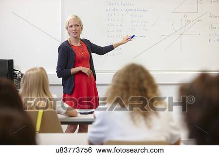 Female teacher using white board in front of class View Large Photo Image Stock Photograph - Female teacher using white board in front of class. Fotosearch