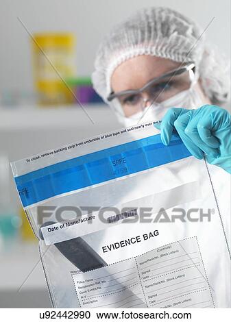Stock Image - Forensic scientist holding evidence bag from crime scene in laboratory. Fotosearch