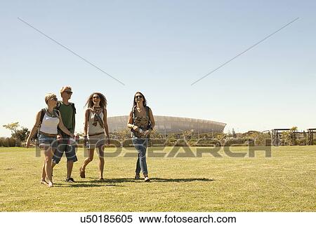 Stock Photography - Four friends walking across park, Cape Town, South Africa. Fotosearch
