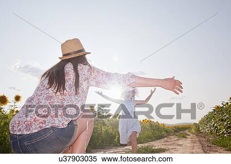 Stock Photography - Girl running through field to mother with open arms. Fotosearch