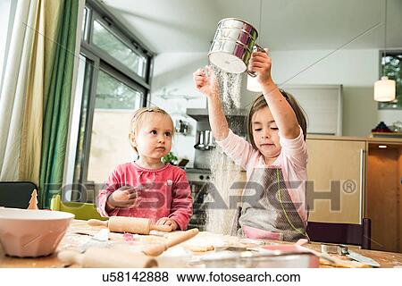 Stock Photo - Girl sieving flour in kitchen. Fotosearch