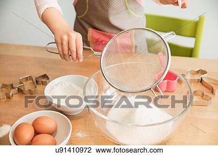 Girl sieving flour into mixing bowl View Large Photo Image Stock Image - Girl sieving flour into mixing bowl. Fotosearch