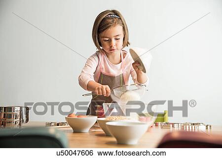 Girl sieving flour into mixing bowl View Large Photo Image Stock Photograph - Girl sieving flour into mixing bowl. Fotosearch