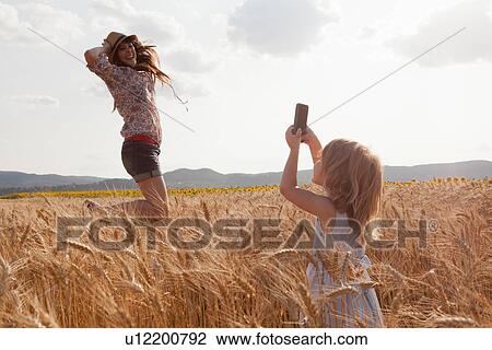 Girl taking photograph of mother in wheat field jumping View Large Photo Image Stock Image - Girl taking photograph of mother in wheat field jumping. Fotosearch