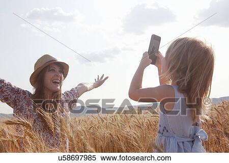 Girl taking photograph of mother in wheat field with arms open View Large Photo Image Stock Photography - Girl taking photograph of mother in wheat field with arms open. Fotosearch