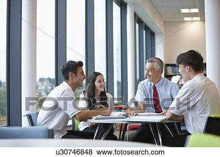 Group of teenagers working with teacher in school class View Large Photo Image Stock Photo - Group of teenagers working with teacher in school class. Fotosearch