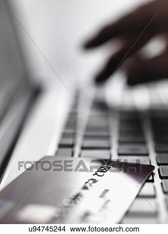 Picture - Hand tapping account details on laptop to illustrate internet shopping and internet fraud. Fotosearch