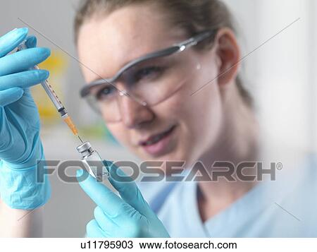Healthworker holding up a syringe and vial, filling syringe in preparation injection View Large Photo Image Stock Image - Healthworker holding up a syringe and vial, filling syringe in preparation injection. Fotosearch