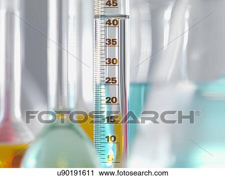 Stock Image - Laboratory glassware in lab, Measuring flasks and cylinders containing chemicals during experiment. Fotosearch