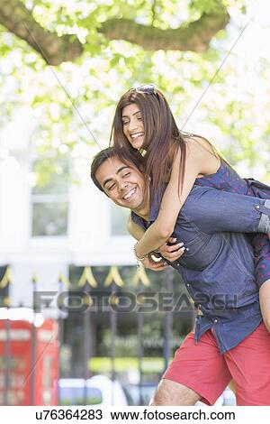Stock Image - Man giving woman piggyback. Fotosearch