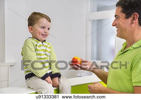 Man giving young boy apple View Large Photo Image Stock Image - Man giving young boy apple. Fotosearch