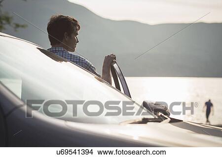 Man in car by lake, Cumbria, England, UK View Large Photo Image Picture - Man in car by lake, Cumbria, England, UK. Fotosearch