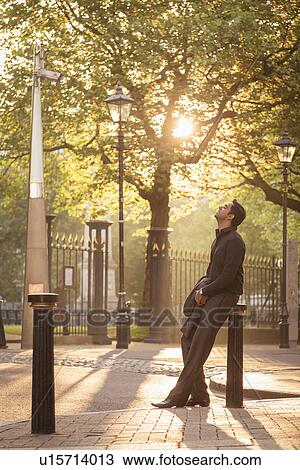 Stock Image - Man leaning on bollard in park, Birmingham, England, UK. Fotosearch
