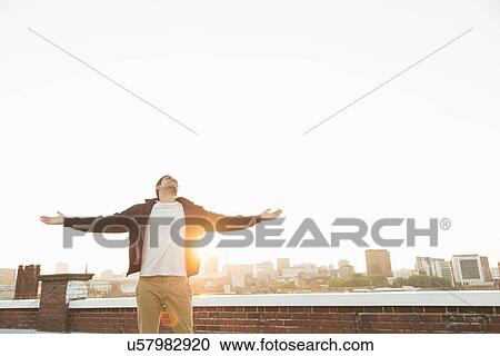 Man on rooftop with arms outstretched View Large Photo Image Stock Image - Man on rooftop with arms outstretched. Fotosearch