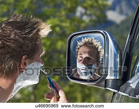 Man using reflection in wing mirror to shave face View Large Photo Image Stock Photo - Man using reflection in wing mirror to shave face. Fotosearch