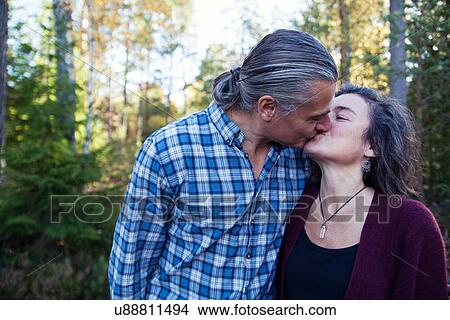 Picture - Mature couple kissing in woods, Mariefred, Sweden. Fotosearch