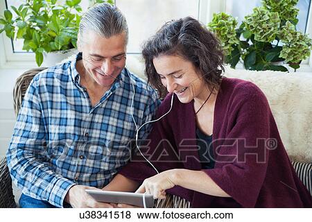 Mature couple listening to music on digital pad View Large Photo Image Stock Photo - Mature couple listening to music on digital pad. Fotosearch