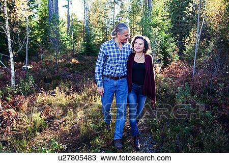 Stock Image - Mature couple strolling in woods, Mariefred, Sweden. Fotosearch